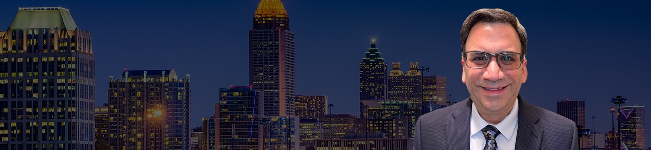 Photo of Glenn T. Stern in a business suit smiling in front of an illuminated city skyline at dusk.